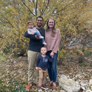 A couple with two children standing outside by a tree in fall