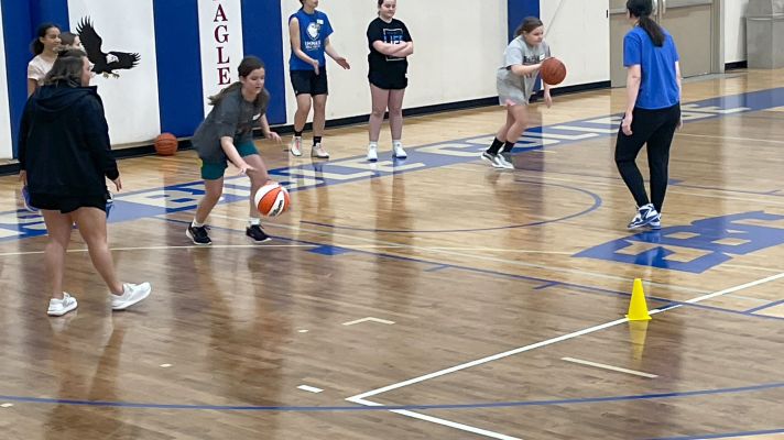 Middle school girls doing basketball dribbling drills