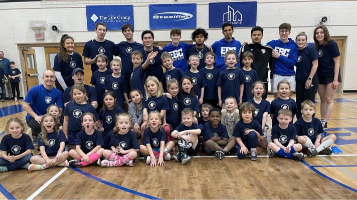 Elementary soccer players pose for group photo with coaches