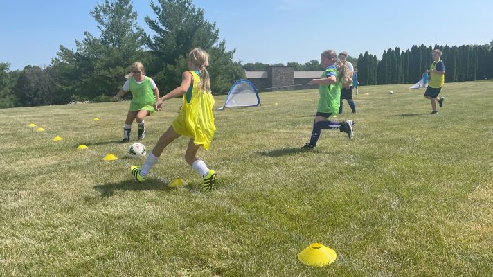 Elementary school girls playing soccer outdoors